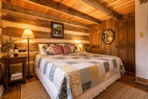 Ein gemütliches Schlafzimmer mit einer Holzwand, einem Bett mit Steppdecke, zwei Nachttischlampen und einer Holztür.