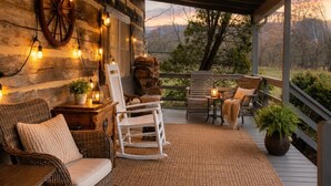 Un espacio de estar al aire libre cubierto con mobiliario de mimbre, un tapete tejido e iluminación con luces colgantes.