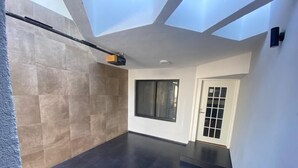 Une pièce spacieuse dotée d’une grande fenêtre, d’une porte avec un panneau en verre et d’un plafond agrémenté de lucarnes.