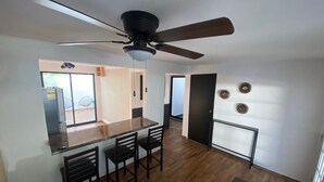 Une cuisine moderne avec un coin repas, un ventilateur de plafond et une vue sur l’extérieur.