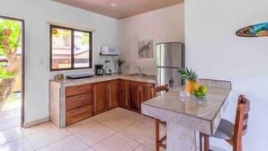 Una cocina compacta con armarios de madera, un refrigerador de acero inoxidable y una mesa de comedor con sillas.