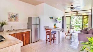 Una cocina moderna con refrigerador, armarios de madera y un comedor con mesa y sillas.
