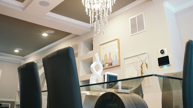 A dining area with a glass table, black chairs, and a chandelier.