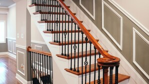 A staircase with wooden steps and black balusters, leading to an upper floor.