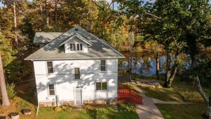 A white house with a gabled roof, a front porch, and a pathway leading to the entrance. - Lakeside Luxury on Upper & Lower Post Lake Channel (Post Lake)
