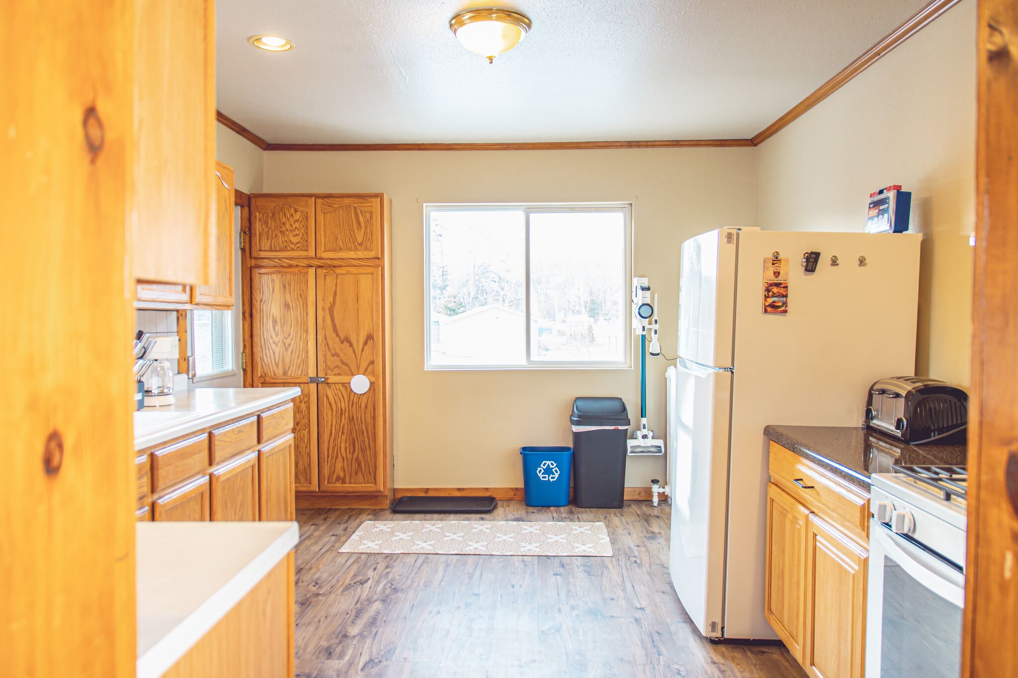 A kitchen with wooden cabinets, a refrigerator, a stove, and a window.