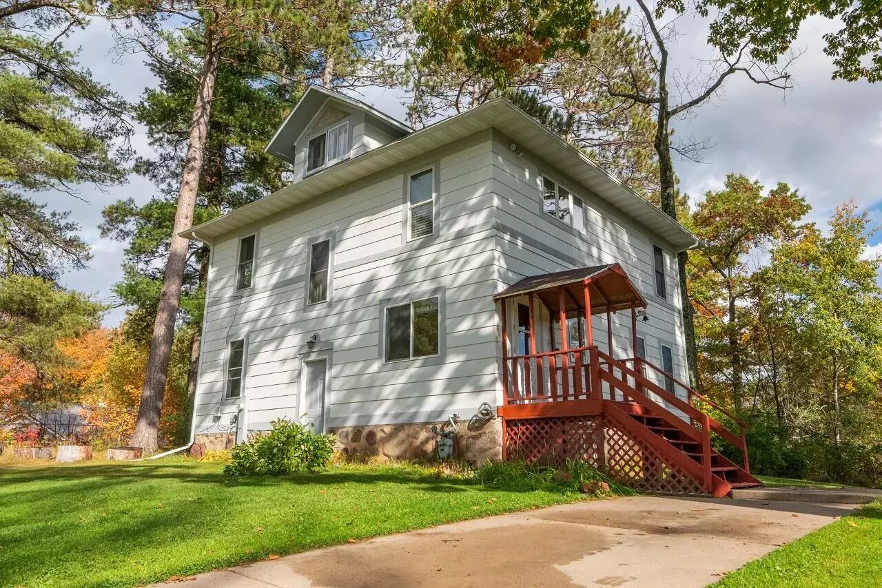 A two-story white house with a red porch and staircase.
