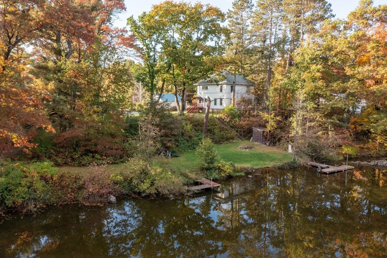 A house surrounded by autumn foliage and a pond.
