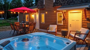 A hot tub on a wooden deck with outdoor furniture and string lights. - Escape Route Retreat · Town Center Retreat* Hot Tub, Game Room, Fire Pit (Lincoln)
