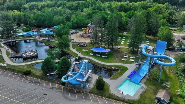 An aerial view of a water park with multiple slides and a pool area, surrounded by dense forest. - Escape Route Retreat · Town Center Retreat* Hot Tub, Game Room, Fire Pit (Lincoln)