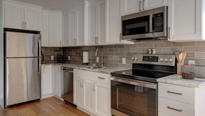 A modern kitchen with white cabinets, stainless steel appliances, and a tiled backsplash. - Escape Route Retreat · Town Center Retreat* Hot Tub, Game Room, Fire Pit (Lincoln)