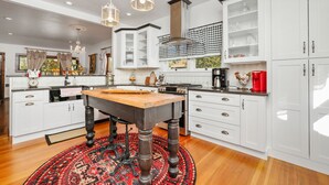 Una cocina con armarios blancos, una mesa de madera y una alfombra roja.