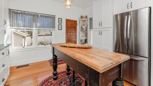 Una cocina con una isla de madera, electrodomésticos de acero inoxidable y un valance de ventana a cuadros.