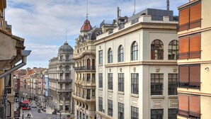 Une vue d’une rue d’une ville, avec des bâtiments historiques, un ciel dégagé et un tramway visible au loin.