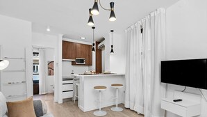 Une cuisine moderne avec des meubles blancs, un four à micro-ondes et un coin bar équipé de tabourets.