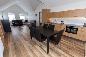 Een moderne keuken met houten kastjes, een eettafel met stoelen en een zichtbare oven.