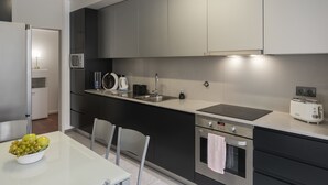 A modern kitchen with a built-in microwave, kettle, and toaster. There is a bowl of fruit on the counter and a sink with a faucet. - City Holidays in Madeira - Madalenas XXI (Funchal)