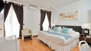 A hotel room with a bed, a chair, a desk, and a nightstand with a lamp and phone. - Hotel boutique Trinidad (Vina del Mar)