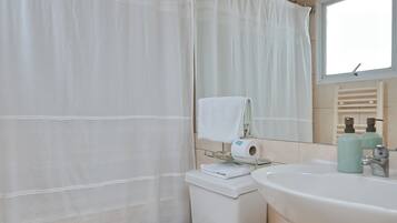 Un baño con inodoro, lavamanos y cortina de ducha.