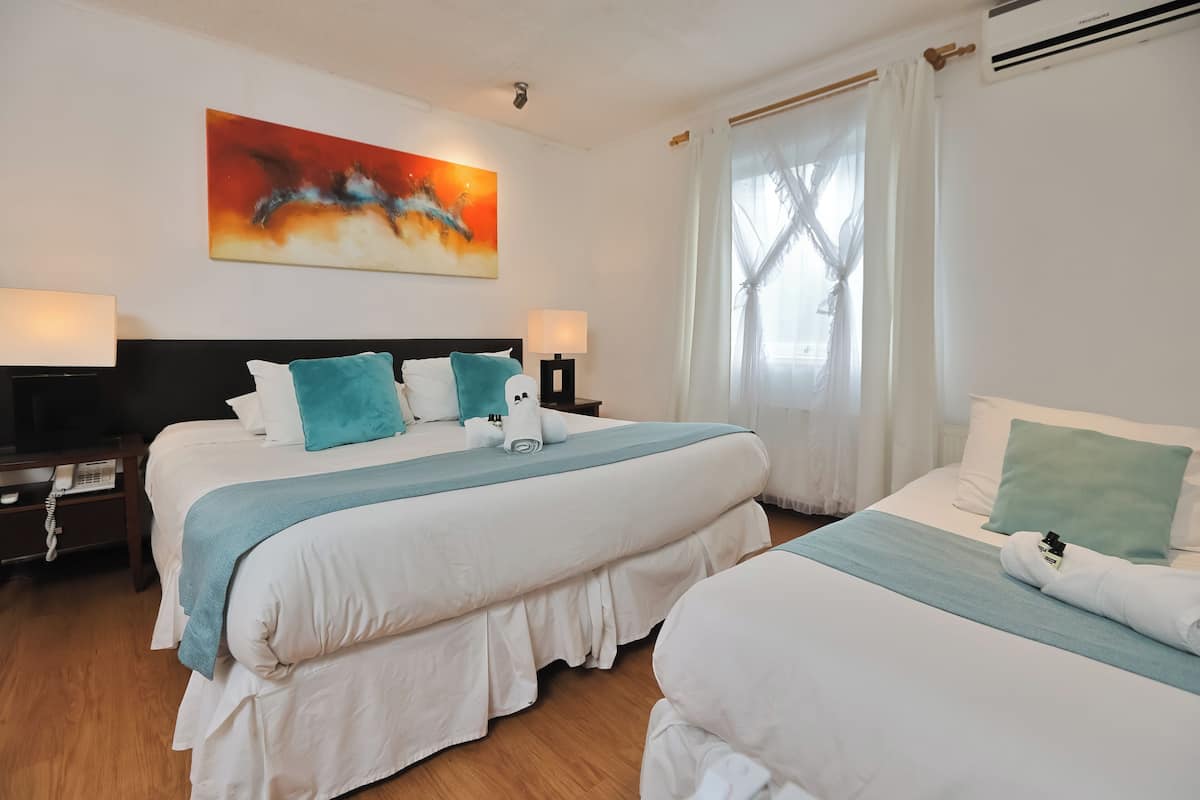 Ein Hotelzimmer mit zwei Betten, einem großen Gemälde, einem Telefon auf dem Nachttisch und einem Fenster mit Vorhängen.