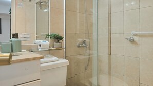 A modern bathroom with a glass-enclosed shower, a toilet, and a sink area with toiletries. - Hotel boutique Trinidad (Vina del Mar)