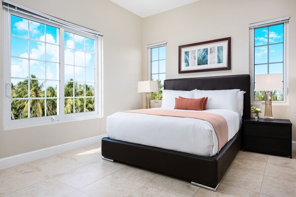 Relax in this serene bedroom with a large bed, framed picture, and a table with a lamp.