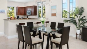 Una cocina moderna con armarios de madera oscura, una isla central y un comedor con mesa y sillas de vidrio.