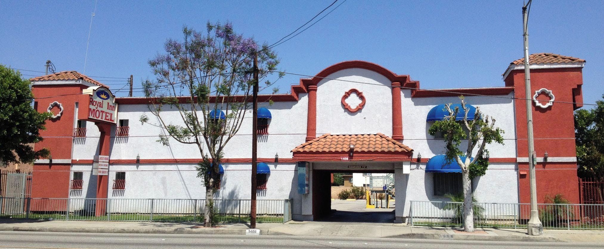A two-story motel with a red and white facade, a clear entrance, and a blue awning over the door.
