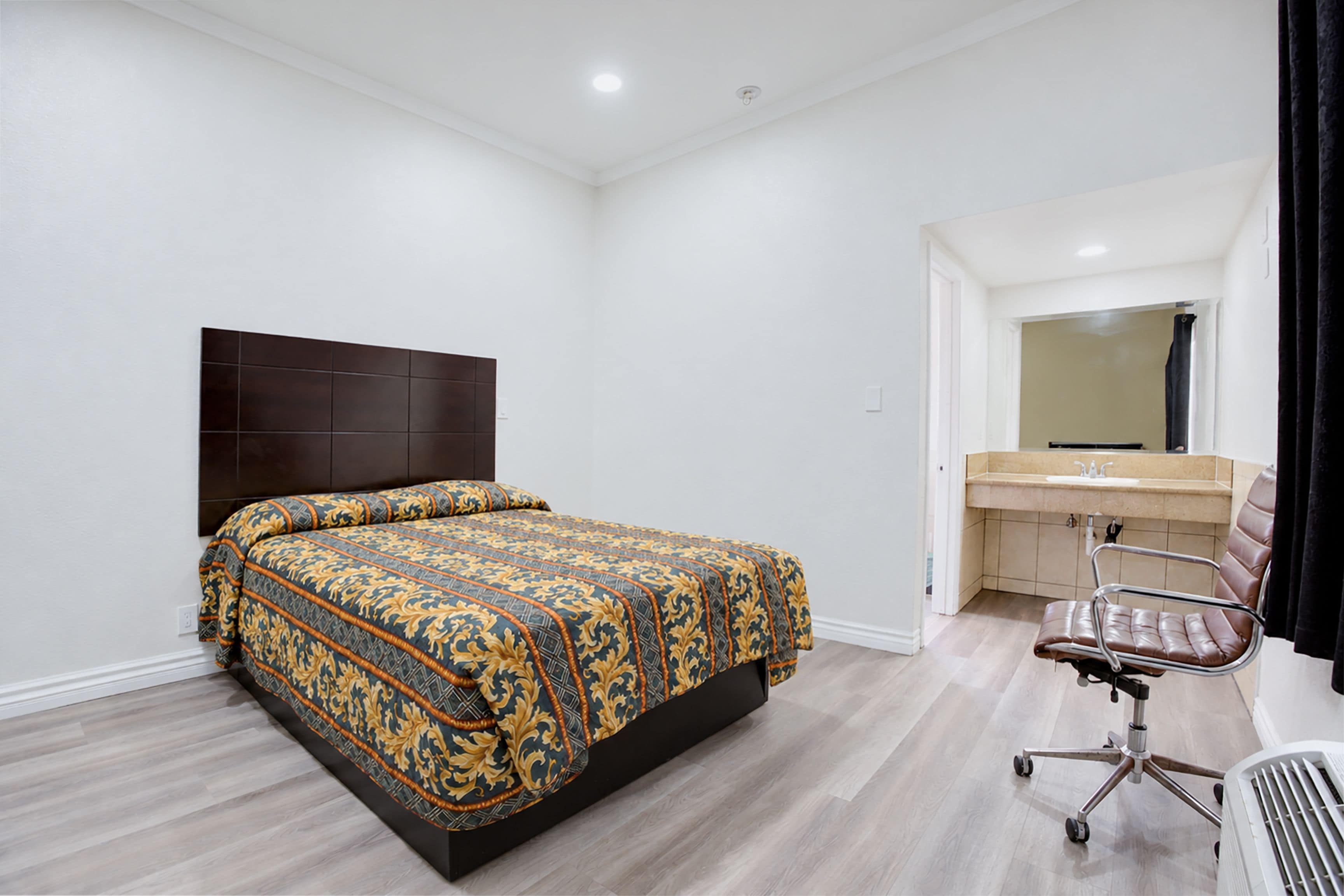 A bedroom with a bed, a desk, and a chair.