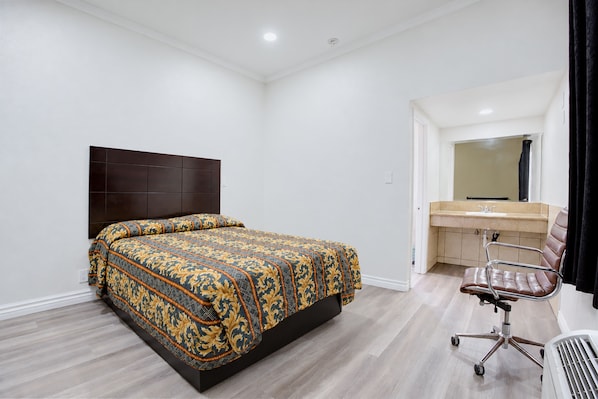 A bedroom with a bed, a desk, and a chair.