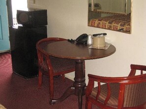 A room with a round wooden table, two chairs, a telephone, and a small decorative item on the table. - Royal Inn Motel, Compton CA (Compton)