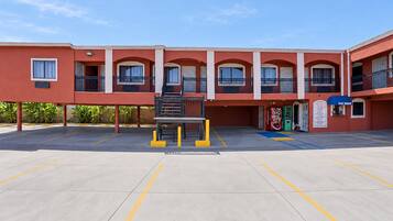 A building with a red facade, multiple balconies, and a parking area with yellow lines.