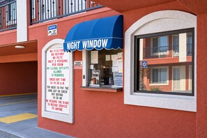 A building with a blue awning and a sign indicating 'No Visitor, No Refund, No Pets, Only 2 Persons Per Room, No Illegal Activity, ID Required, Check Out Time 10:30 A.M., Same Day Payment or Check Out Before 10:30 A.M., We Reserve the Right to Refuse Service to Anyone.'