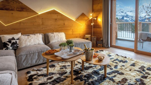 A cozy living room with a sofa, a coffee table, and a rug. - Chalet Mevi - family break in the Alps 13p, great location - OVO Network (Crest-Voland)