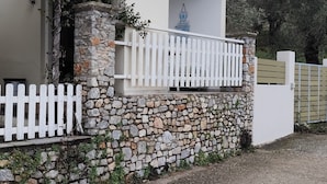A house with a stone wall, a white picket fence, and a red-tiled roof. - Alexia studios (Skiathos)