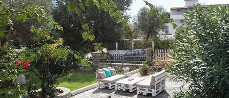 Une terrasse extérieure avec un sol en pierre, des meubles blancs et des plantes en pot.