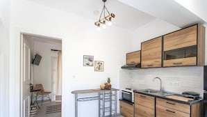 A modern kitchen with wooden cabinets, a central island, and a hanging light fixture. - Alexia studios (Skiathos)