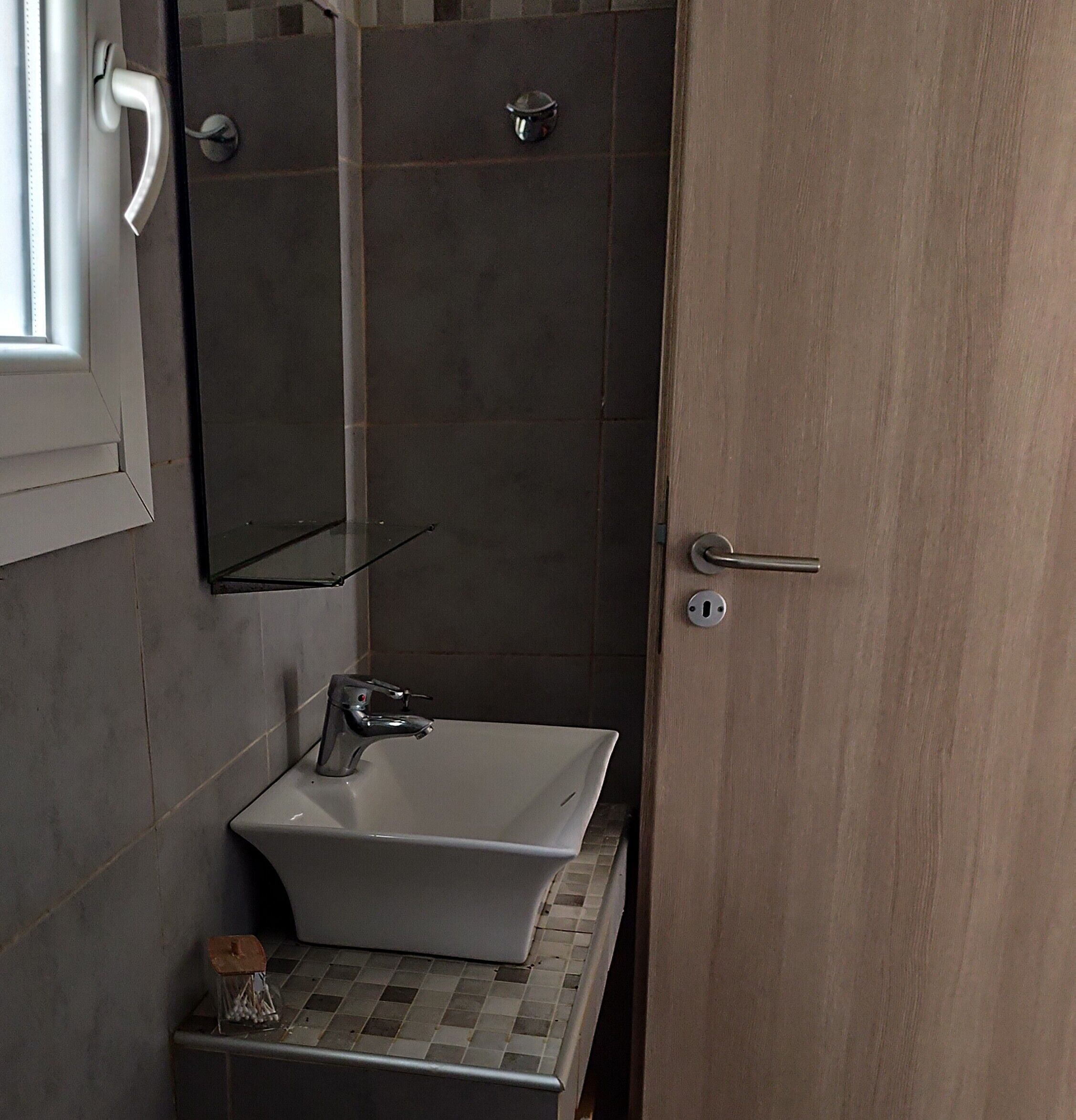 A bathroom with a white sink, a mirror, and a shower area.