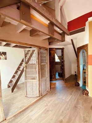 A spacious interior with a wooden staircase, a decorative door, and a high ceiling with exposed beams. - House with pool, sleeps 8 (4 adults and 4 children) (La Croix Hélléan)