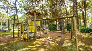 A playground with a wooden climbing structure, a slide, and swings.
