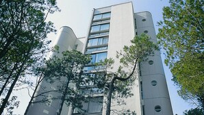 A modern building with a curved facade, multiple windows, and a central entrance.