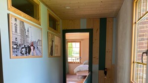 A narrow hallway with wooden floors and walls, leading to a bedroom with a bed and a window. - Comfortable house in the heart of Normandy (Flancourt-Crescy-en-Roumois)