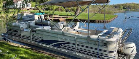 A boat docked at a marina with a canopy, seating, and a Yamaha outboard motor.