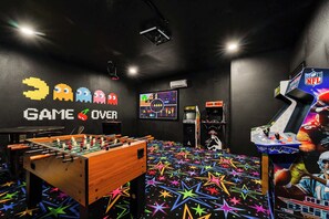 A room with a foosball table, arcade games, and a wall with 'GAME OVER' text. - Elite 9BR Disney Villa | Home Theater and Pool (Davenport)