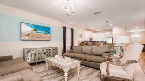 A living room with a sofa, a coffee table, a decorative cabinet, and a painting of a beach scene.