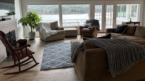Ein geräumiges Wohnzimmer mit Kamin, einem großen Fenster mit Seeblick und einer gemütlichen Sitzecke.