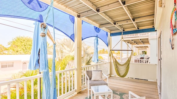 A covered outdoor area with a hammock, white furniture, and a view of palm trees. - Gulf views w/scenic elevated sundeck, heated shared pool, boat dock availability (Marathon)