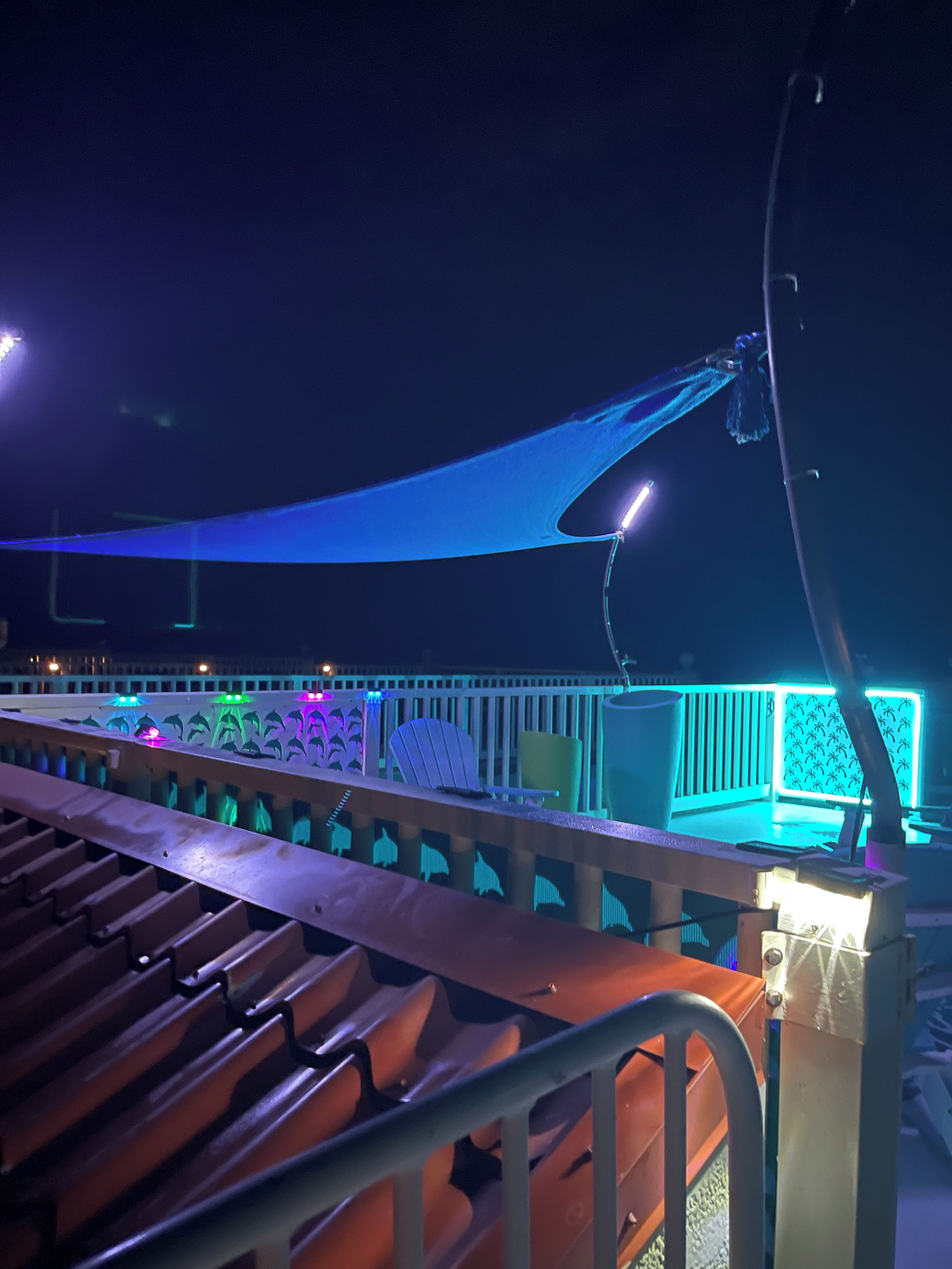 A nighttime outdoor seating area with a canopy, chairs, and a table.