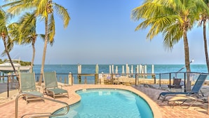 A pool area with lounge chairs, a pool, and a view of the ocean. - Gulf views w/scenic elevated sundeck, heated shared pool, boat dock availability (Marathon)