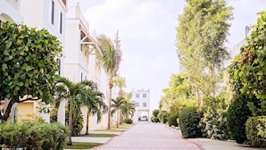 A paved pathway lined with palm trees and greenery, leading to a building with a red-tiled roof. - Gulf views w/scenic elevated sundeck, heated shared pool, boat dock availability (Marathon)